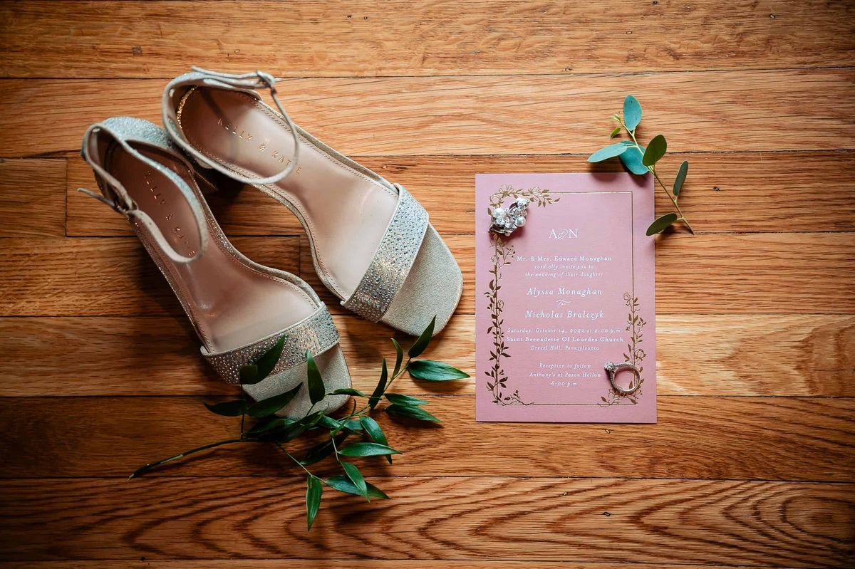 Bridal shoes and invitation on a wood floor