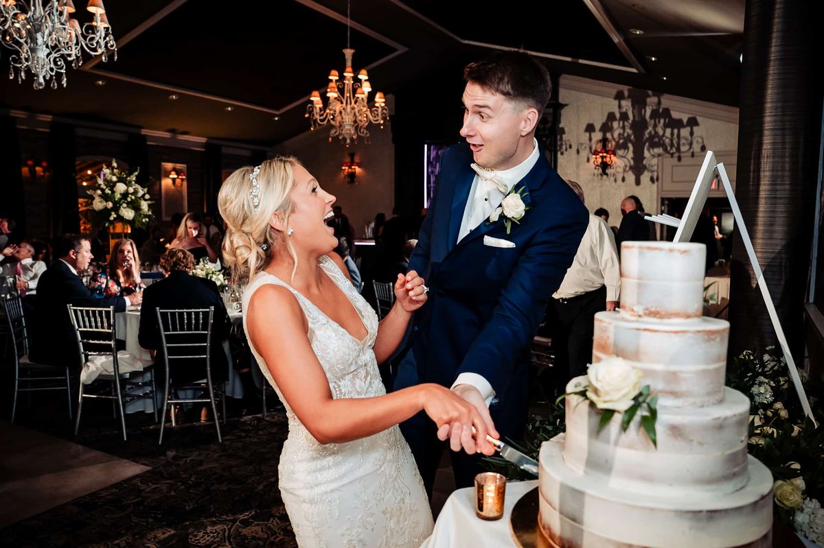 Couple laughing as they cut the cake