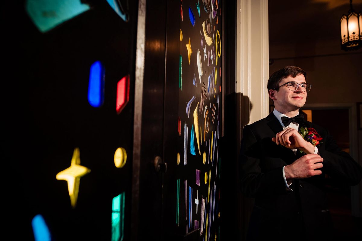 Groom waiting beside stained glass