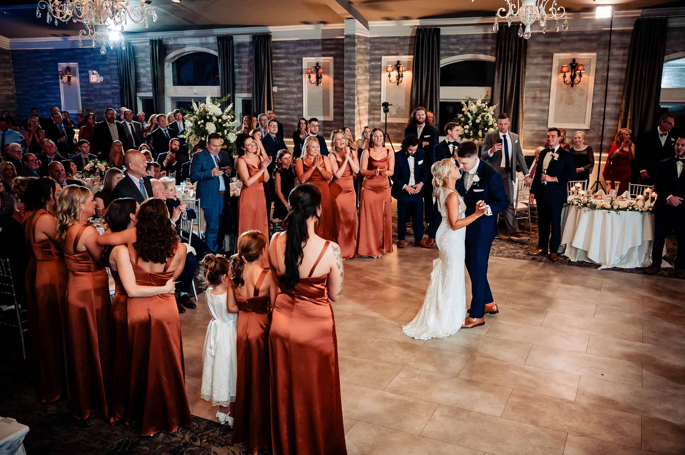 Newlyweds share their first dance in The Ballroom as the bridal party and guests look on and cheer